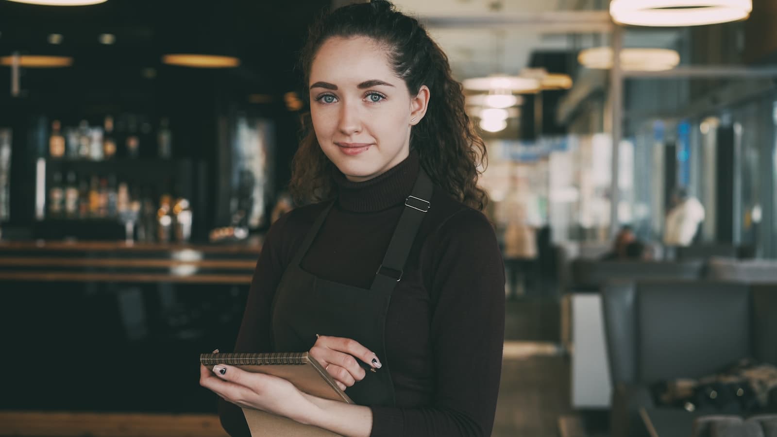 A restaurant operator holding a tablet in the venue, representing the business side of digital menu setup and management