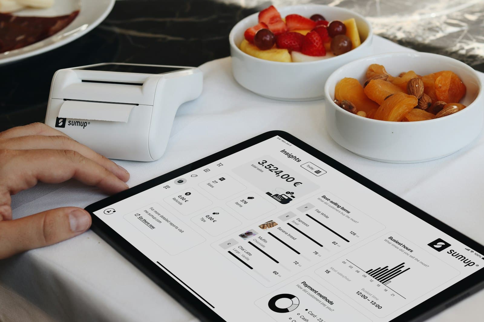 Um painel de cardápio em tablet ao lado de itens de serviço de mesa, representando atualização de preços sem reimpressão